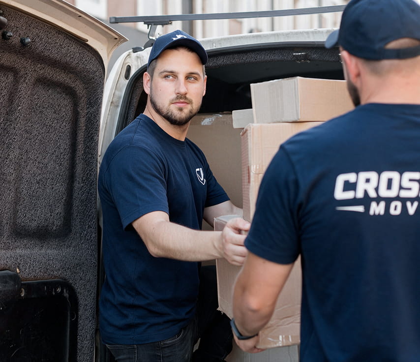 Two Cross Fit Moving crew members loading boxes into the back of a van